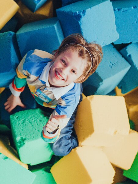 A happy child plays in colorful foam blocks. | © Lex Karelly