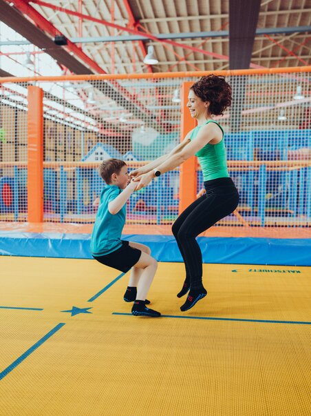 A woman helps a child jump on a trampoline. | © Lex Karelly