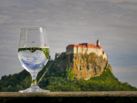 A glass of water in front of Riegersburg castle in the background. | © Steiermark Tourismus - Manfred Polansky