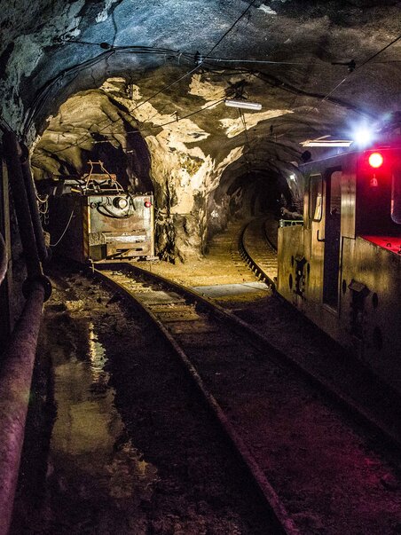 Dark mine tunnel with a locomotive and tracks. | © VA Erzberg - Fotograf August Zöbl