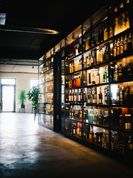 Modern bar featuring a glass shelf filled with various spirits. | © David Gölles