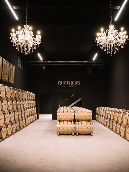 Interior view of a whiskey storage with barrels and chandeliers. | © David Gölles