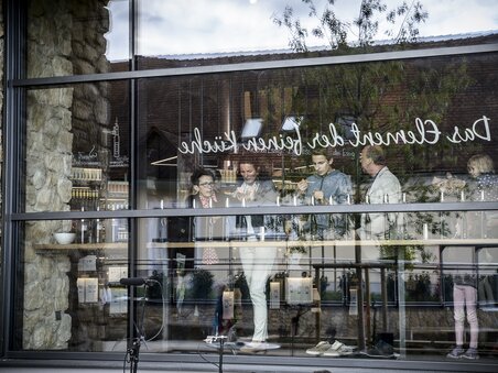Five people at gin production Gölles, looking intently at a table behind glass. | © Ulrike Rauch