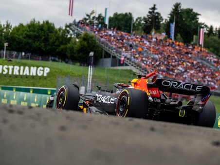 Formula 1 race car speeding on the Red Bull Ring racing circuit, with packed grandstands full of cheering spectators. | © Joerg Mitter - Red Bull Content Pool
