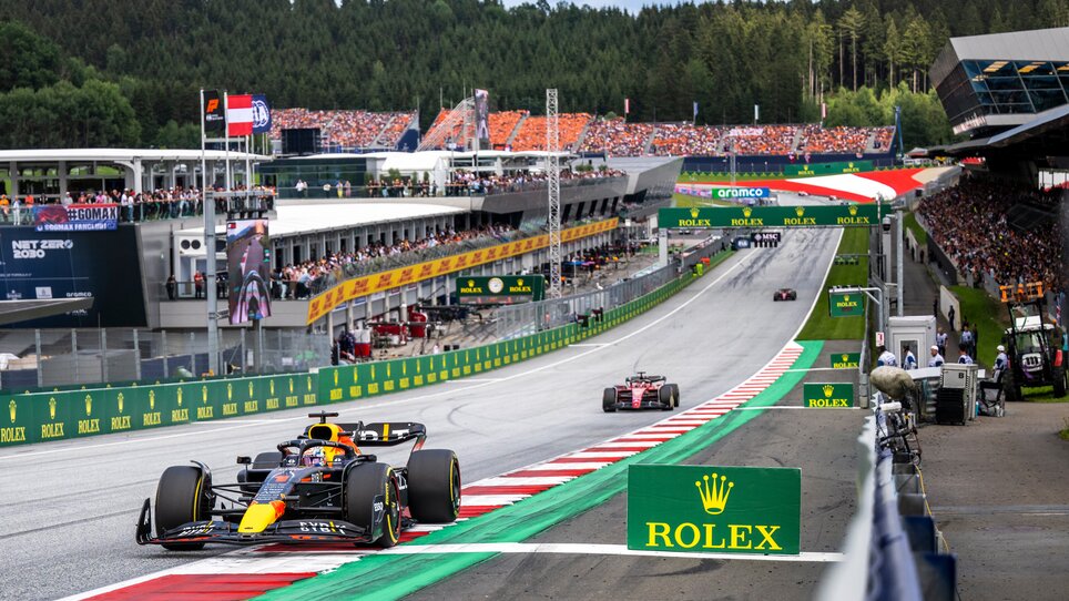 Formula 1 race cars speeding on the Red Bull Ring racing circuit, with packed grandstands full of cheering spectators. | © Joerg Mitter - Red Bull Content Pool