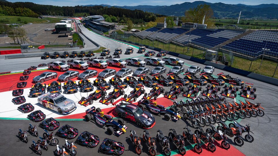 Race cars, sports cars, and motorcycles parked in formation on the Red Bull Ring in Spielberg – group photo of all Red Bull vehicles. | © Red Bull Content Pool