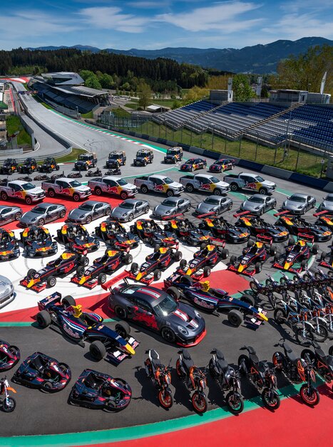 Race cars, sports cars, and motorcycles parked in formation on the Red Bull Ring in Spielberg – group photo of all Red Bull vehicles. | © Red Bull Content Pool