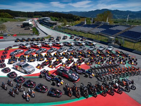 Race cars, sports cars, and motorcycles parked in formation on the Red Bull Ring in Spielberg – group photo of all Red Bull vehicles. | © Red Bull Content Pool