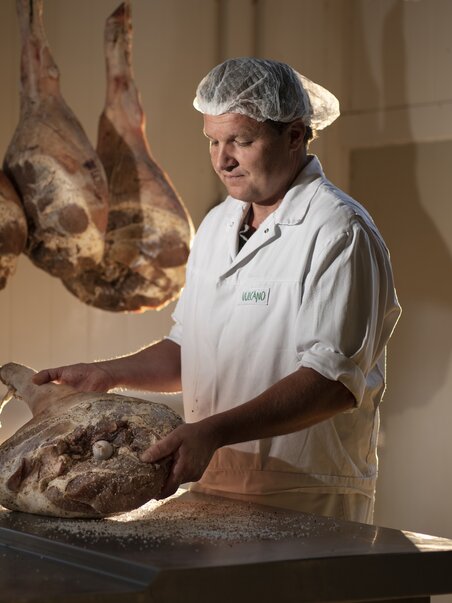 A butcher displays a large ham in the Vulcano Experience. | © Vulcano