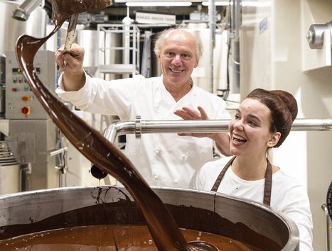 Two people working in a chocolate factory with liquid chocolate. | © Zotter Schokolade