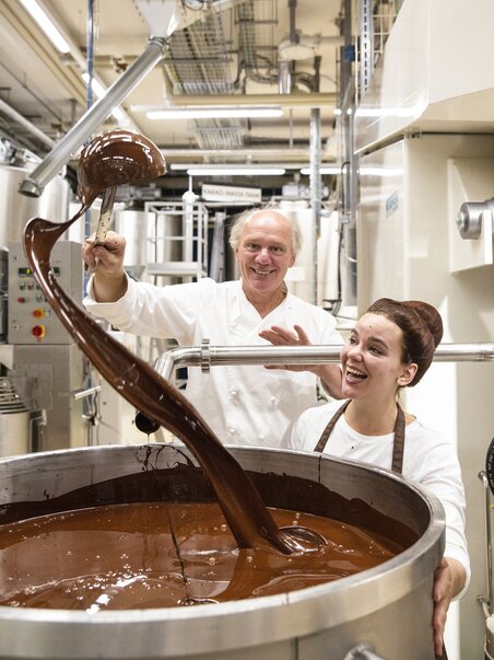 Two people working in a chocolate factory with liquid chocolate. | © Zotter Schokolade