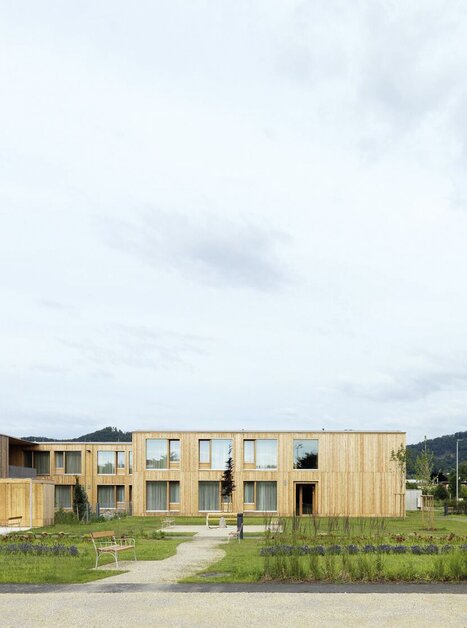 Ein modernes Gebäude aus Holz in einer grünen Umgebung mit Bäumen und Hügeln. | © Paul Ott