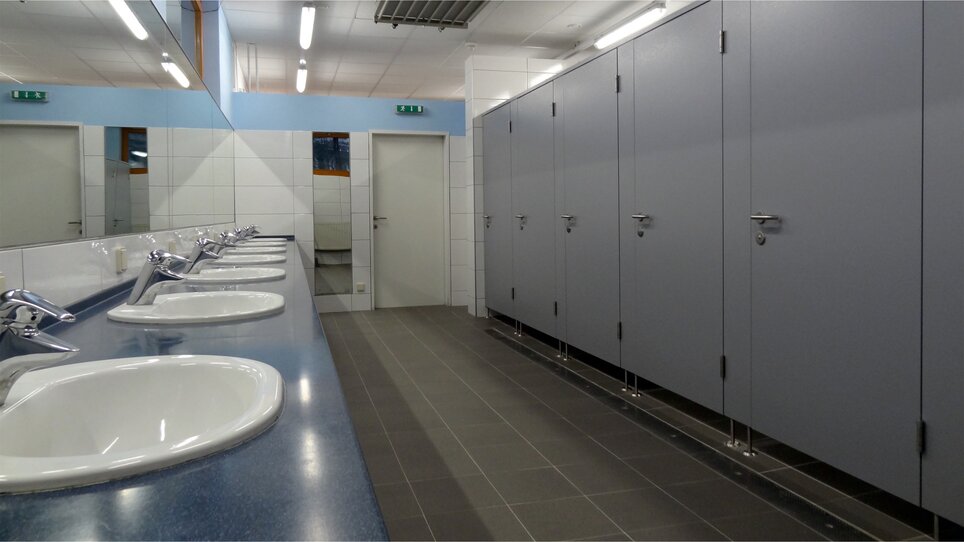 Innenansicht einer öffentlichen Toilette mit Waschbecken und Kabinen. | © Alfred Chyba 