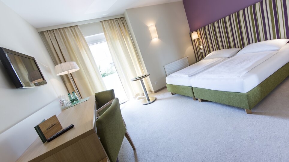 Camera d'albergo luminosa e moderna con letto matrimoniale e scrivania. | © Bauernwirt 