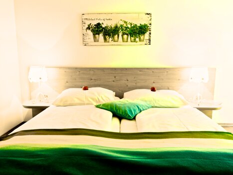 A double room with two beds, pillows, and a plant picture on the wall. | © Zur Steirerstubn