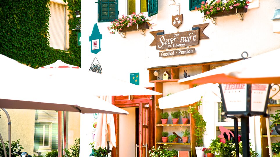 Exterior view of the guesthouse with plants and outdoor tables. | © Zur Steirerstubn