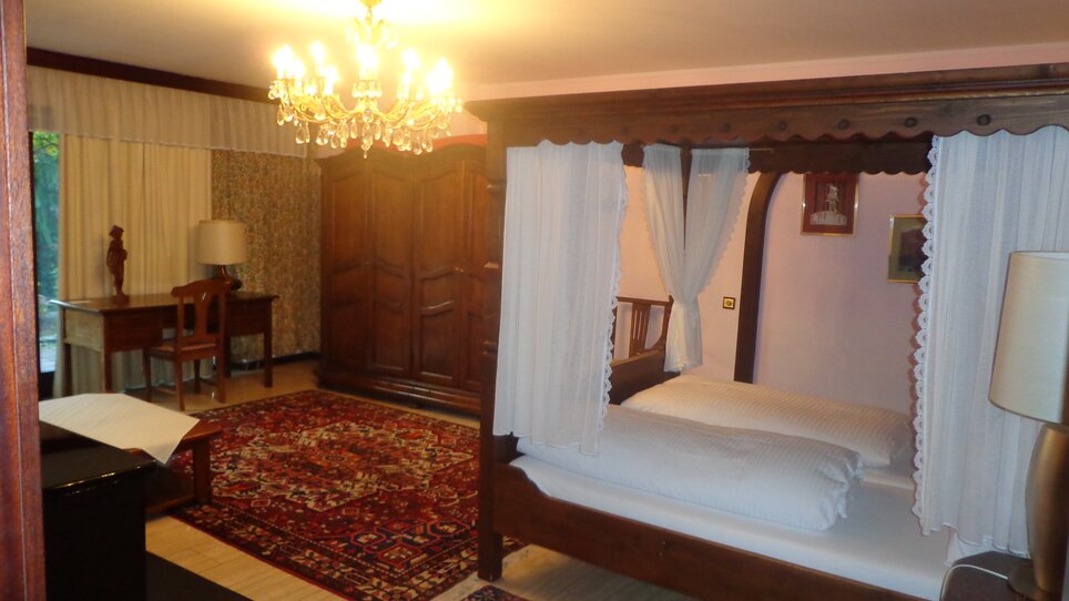Spacious bedroom with a canopy bed at the Landgasthof Häuserl im Wald. | © Legenstein