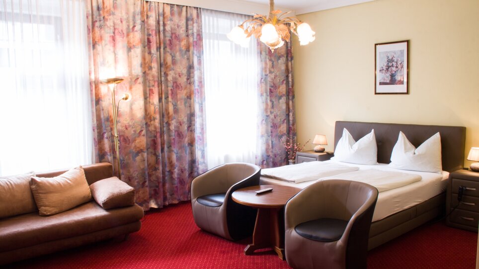 Elegantes Hotelzimmer mit Doppelbett, Sofa und Sitzecke. | © Hotel Alter Telegraf