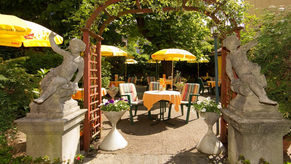 Blick auf den Garten mit Statuen und Sonnenschirmen. | © Foto Schmickl