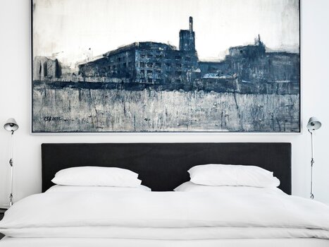 Una camera elegante con un grande dipinto sopra il letto. | © Augarten Art Hotel
