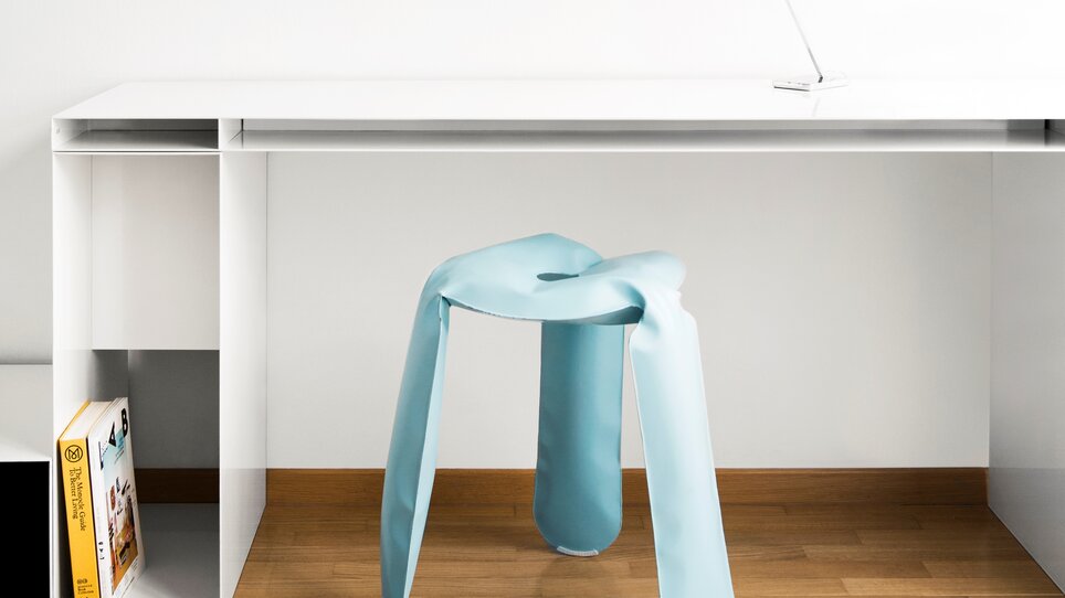 Ein stilvoller blauer Hocker vor einem eleganten Schreibtisch. | © Augarten Art Hotel