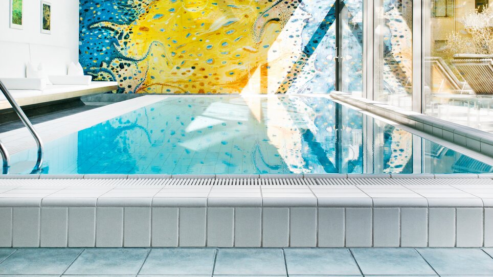 Heller Innenpool mit buntem Wandgemälde und großen Fenstern. | © Augarten Art Hotel