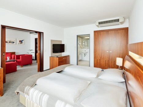 Vista di una camera d'hotel con letto matrimoniale e area giorno adiacente. | © Austria Trend Hotel Europa