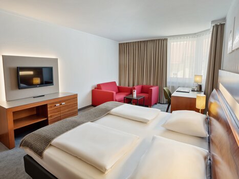 Una camera dell'Austria Trend Hotel Europa con un letto matrimoniale, TV e area salotto. | © Austria Trend Hotel Europa