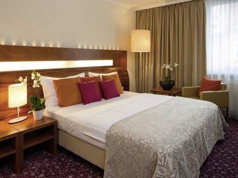 Una camera d'albergo elegante con un grande letto e cuscini decorativi. | © Austria Trend Hotel Europa Graz