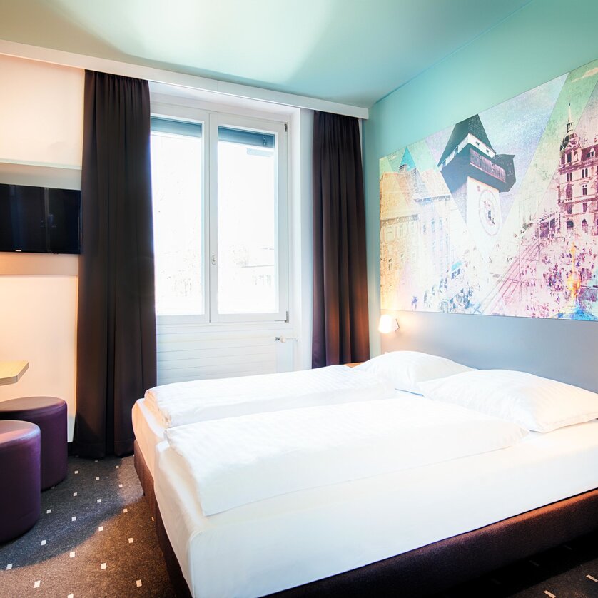 A cozy hotel room at B&B Hotel Graz-Hbf with twin beds and modern furniture. | © B&B Hotels 2023
