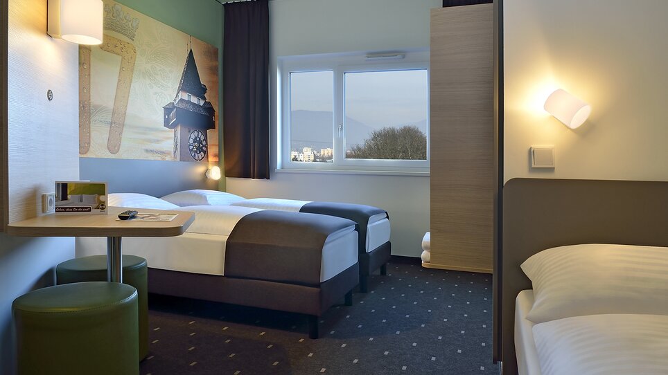 Zweibettzimmer mit extra Bett und Blick auf die Stadt. | © B&B Graz City Süd
