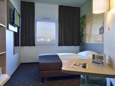 Blick auf ein Einbettzimmer mit Fernseher und Tisch. | © B&B Graz City Süd
