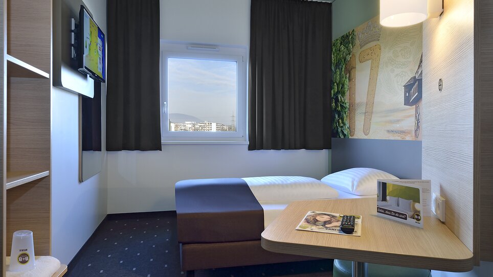 Blick auf ein Einbettzimmer mit Fernseher und Tisch. | © B&B Graz City Süd