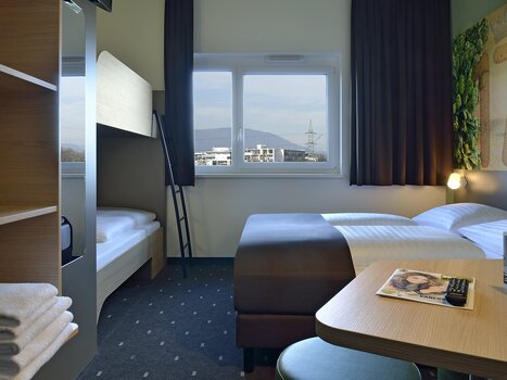 Einblick in ein Hotelzimmer mit Doppelbett und einem Hochbett. | © B&B Graz City Süd