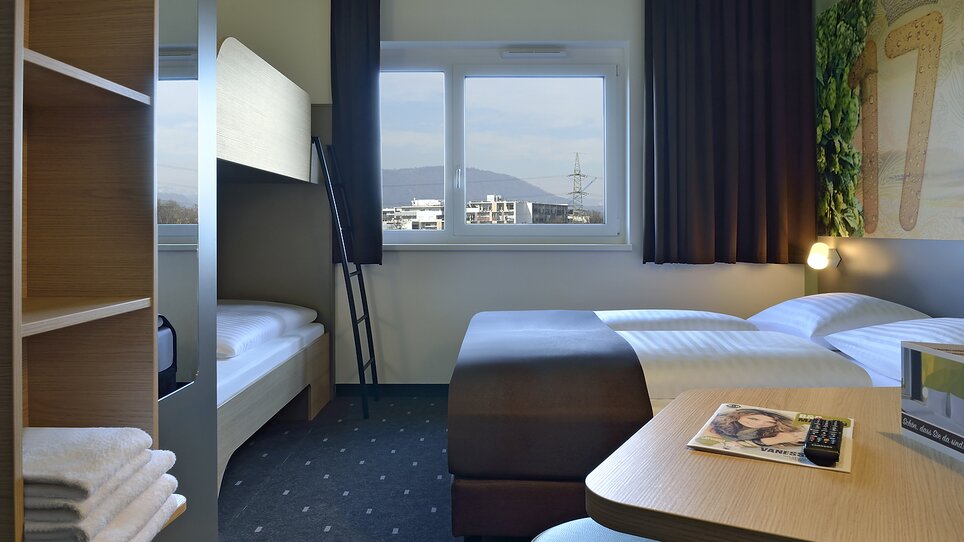 Einblick in ein Hotelzimmer mit Doppelbett und einem Hochbett. | © B&B Graz City Süd