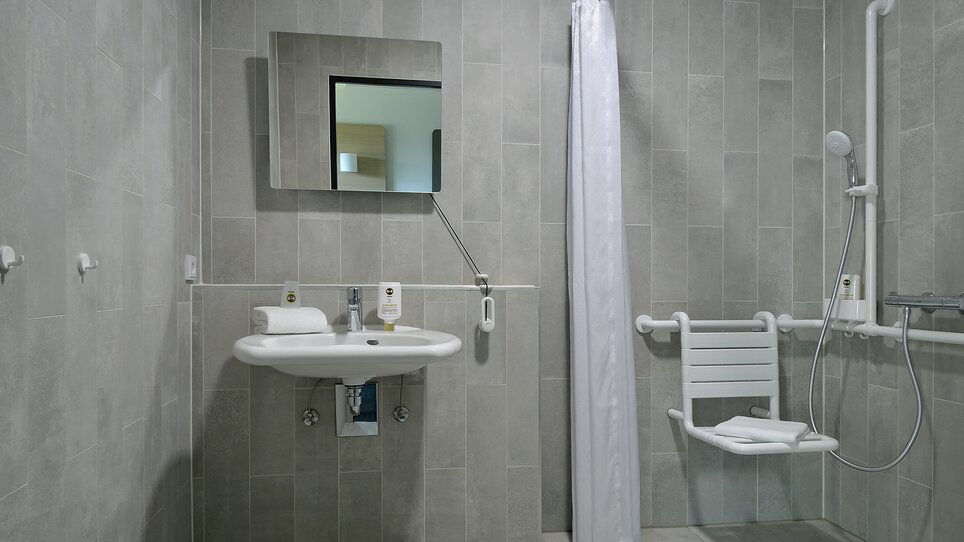 Ein barrierefreies Bad mit Haltegriffen und Duschstuhl. | © B&B Hotel Graz City Süd