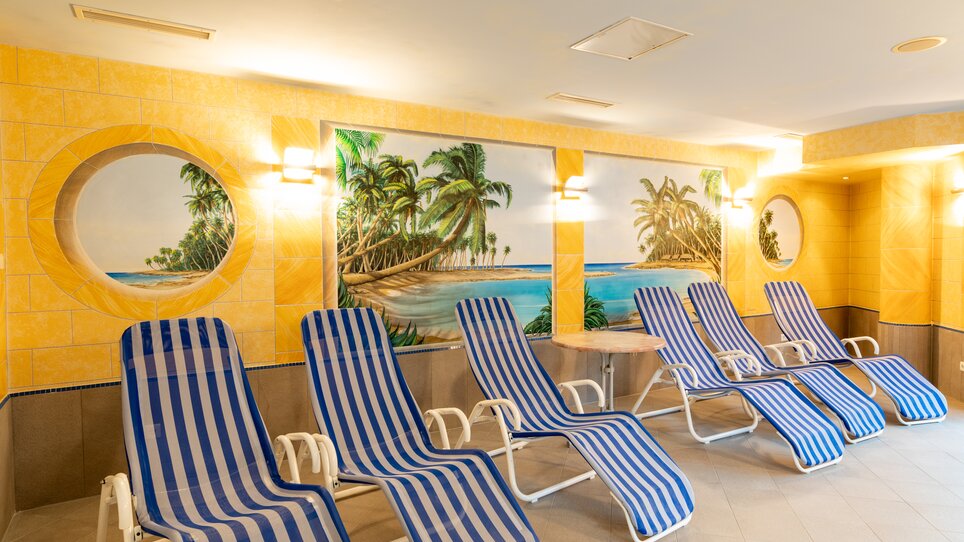 Relaxation area in Bokan exclusiv Hotel-Gasthof featuring loungers and a tropical wall painting. | © Harry Schiffer