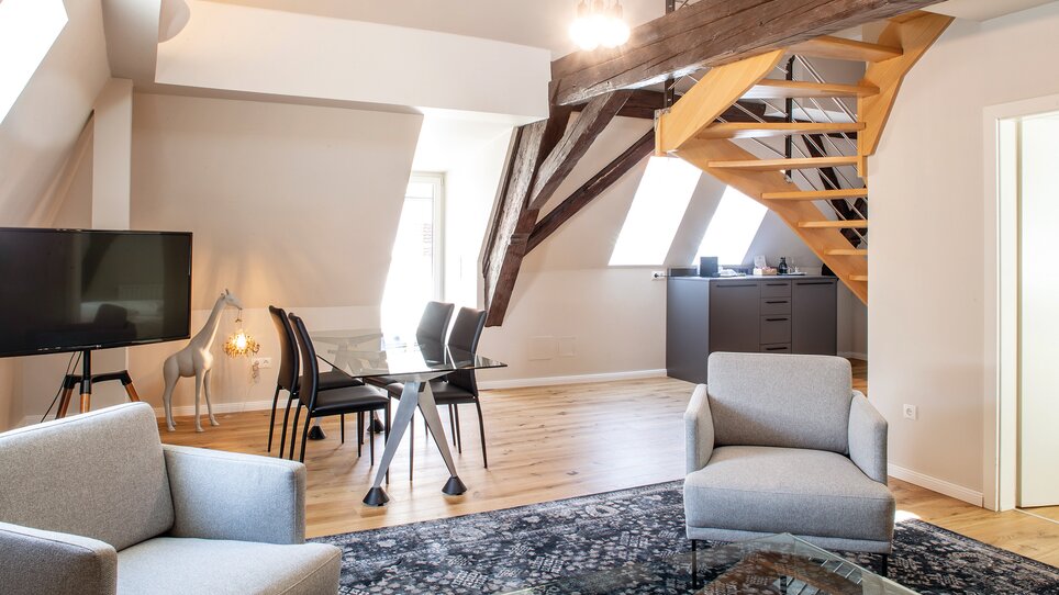 Cozy living and dining area with stairs and windows. | © Robert Illemann