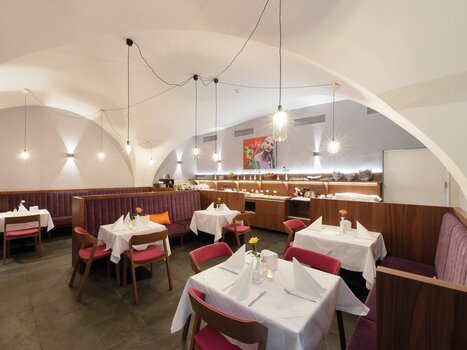 Bright restaurant with white tablecloths and colorful chairs. | © Robert Illemann