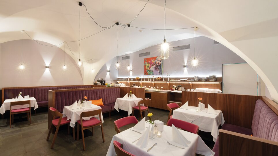 Bright restaurant with white tablecloths and colorful chairs. | © Robert Illemann