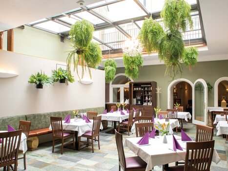 Interior of a restaurant with plants and table settings. | © Robert Illemann