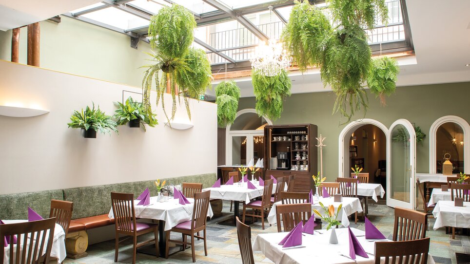 Interior of a restaurant with plants and table settings. | © Robert Illemann