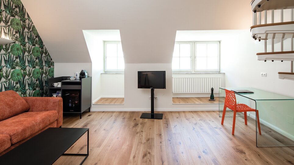 Bright living area with sofa, TV, and desk in the attic. | © Robert Illemann