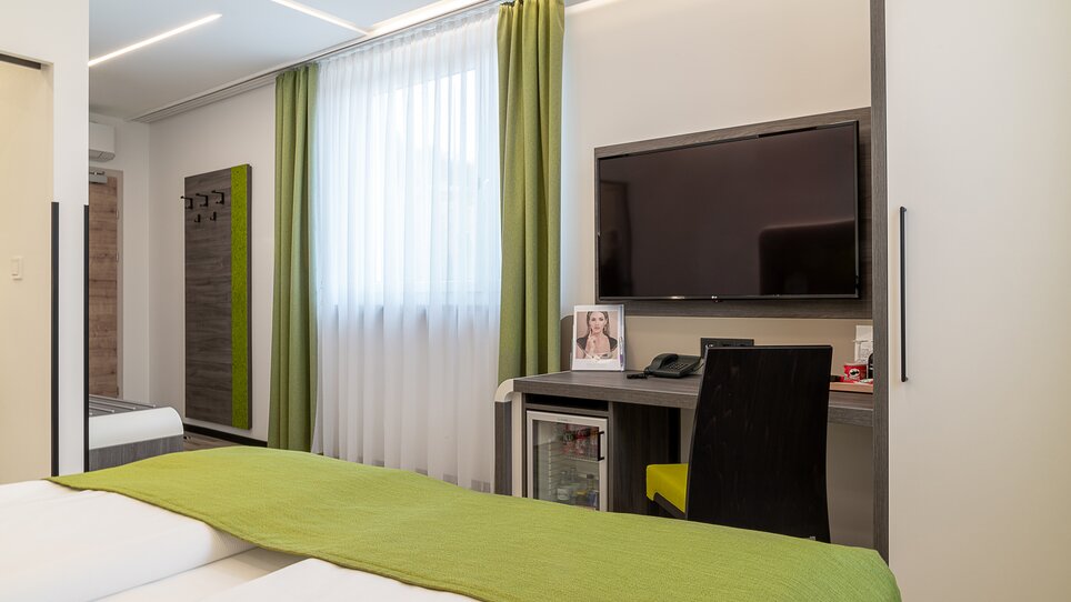 Una camera d'hotel moderna con TV, scrivania e finestra. | © Chrizz Rooms