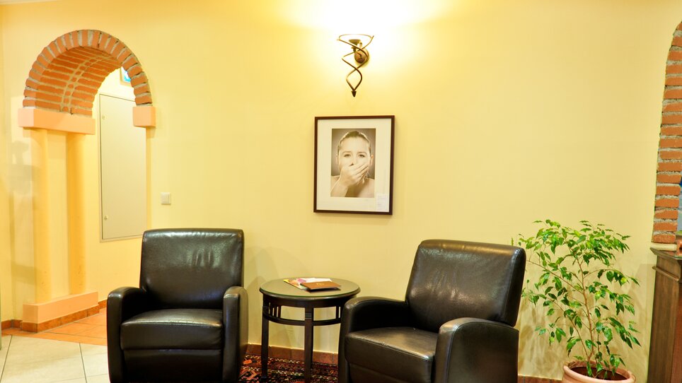 Zwei schwarze Sessel und ein Tisch in einem Raum mit Pflanzen und Wandbild. | © Hotel Feichtinger