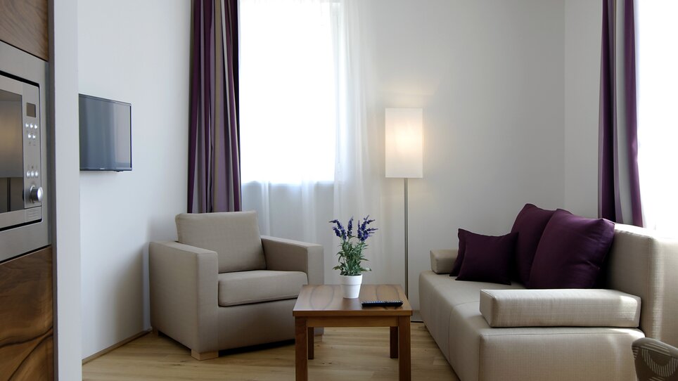 Helles Wohnzimmer mit Sofa und Sessel in neutralen Farben. | © Hotel Feichtinger
