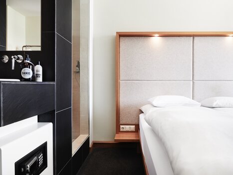 A view of a modern bedroom with a bathroom and beds. | © Weitzer Hotels
