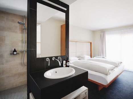 Interior view of a hotel room with bath area and double bed. | © Weitzer Hotels