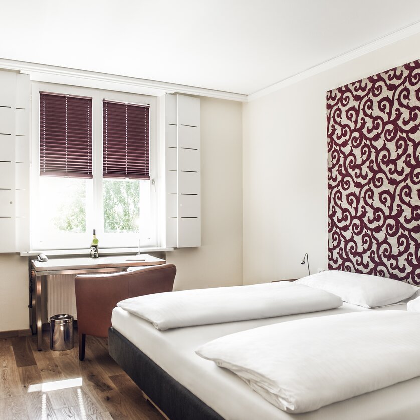 Ein helles Hotelzimmer mit zwei Betten, Schreibtisch und Fenster. | © Weitzer