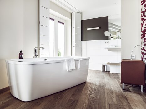 Modern bathroom with freestanding bathtub and wooden floor. | © Weitzer